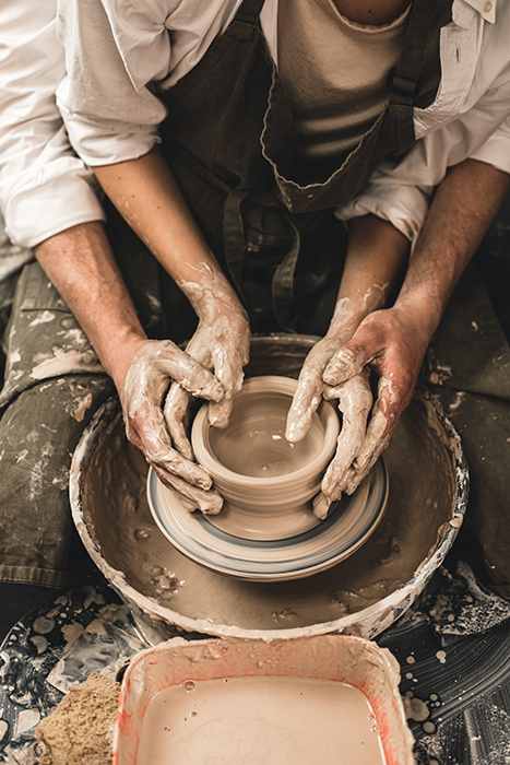 A pair of hands cradling a handmade ceramic cup, the warmth and texture of a genuinely local moment